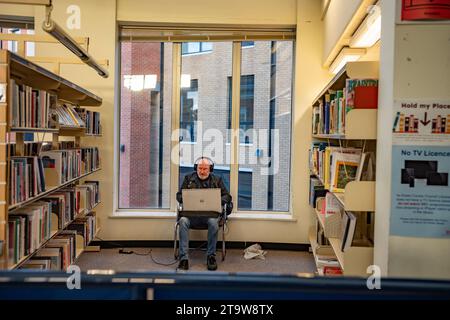 Braintree Essex Inghilterra. Nov 2023 Man Alone nella libreria Braintree con cuffie e laptop. Foto Stock