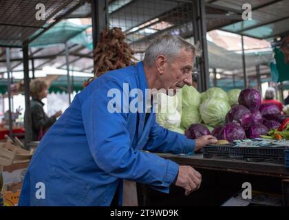 Belgrado, Serbia, 10 novembre 2023: Un venditore in un lavoro dietro una stalla al mercato verde Foto Stock