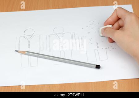 Il concetto di licenziamento o riduzione. Le mani delle donne si puliscono con una gomma una persona disegnata con una matita. Foto Stock