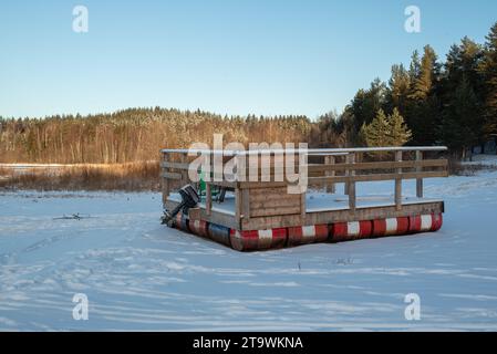 Una zattera da bagno con fusti di olio vuoti mentre galleggia su una spiaggia innevata con un cielo blu sullo sfondo, immagine di Mellansel Svezia. Foto Stock