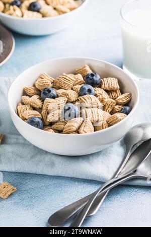 Il concetto di una sana colazione a base di yogurt vegetariano, cereali integrali, frutta fresca su un tavolo blu su uno sfondo bianco della cucina. Vista frontale Foto Stock