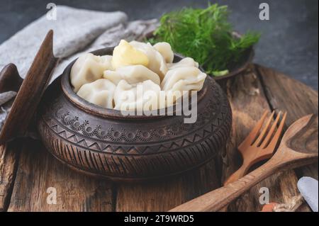 Gnocchi fatti in casa russi in una ciotola di argilla fatta a mano e utensili in legno ecologici con forchetta e cucchiaio. Foto Stock