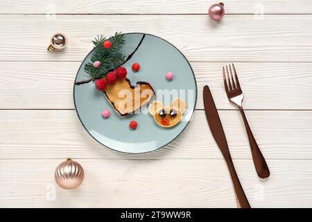 Piatto con pancake a forma di calza e renna su un tavolo di legno bianco. Festeggiamenti di Natale Foto Stock