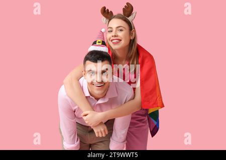 Giovane coppia con bandiera LGBT su sfondo rosa Foto Stock