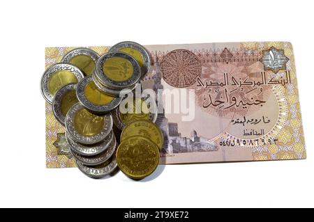 Pile di 1 LE EGP una sterlina egiziana in contanti e 50 cinquanta piaster egiziani monete da mezza sterlina su una banconota da sterlina egiziana isolata su bac bianco Foto Stock