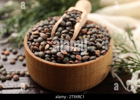 Lenticchie crude e cucchiaio in ciotola su tavolo di legno, primo piano Foto Stock