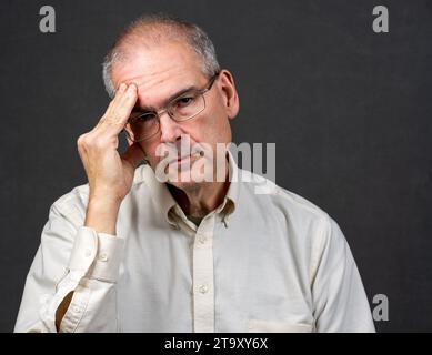 Un uomo di 60 anni tiene il lato della testa in disagio Foto Stock