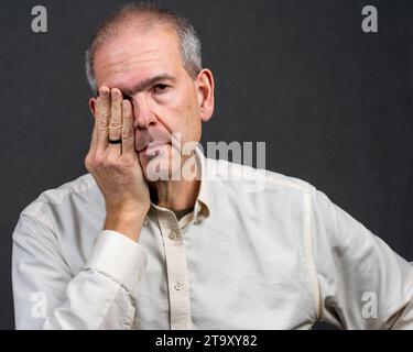 Un uomo di 60 anni tiene il lato della testa in disagio Foto Stock