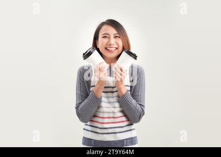Simpatica e sorridente giovane donna asiatica in grembiule che regala caffè, tè e bevande calde Foto Stock