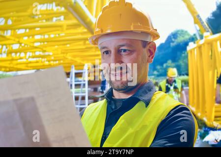Ritratto di giovane è ingegnere indossare casco sorriso soddisfatto in cantiere, architetto o appaltatore in piedi e le braccia incrociate con con con Foto Stock
