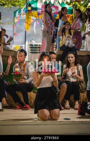 Bangkok, Thailandia. 27 novembre 2023. Tailandesi e stranieri sono visti con il loro krathong, sulla riva del lago, durante il magico Loy Krathong Festival, al Jodd Fairs Dan Neramit, a Bangkok. Loy Krathong 'per galleggiare rituale vaso o lampada' è un festival thailandese celebrato ogni anno in tutta la Thailandia†e nei paesi vicini, dove la notte della luna piena, i Krathong, decorati con foglie di banana riccamente piegate, tre bastoncini di incenso, e una candela, vengono lanciate dai thailandesi, su un fiume, un canale o uno stagno, facendo un desiderio come fanno. Credito: SOPA Images Limited/Alamy Live News Foto Stock