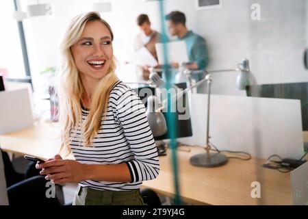 Ritratto di un attraente giovane africana imprenditrice sorridere mentre in piedi da windows in ufficio Foto Stock