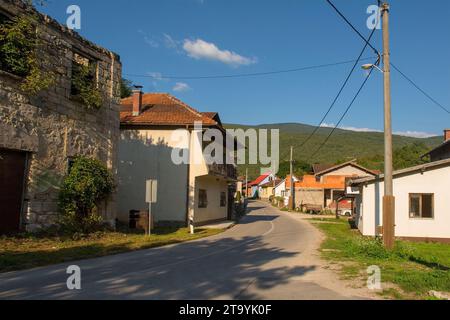 Una tranquilla strada residenziale nel villaggio di Kulen Vakuf nel Parco Nazionale di una con una casa abbandonata sulla sinistra. Una-sana Canton, Bosnia Foto Stock