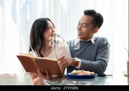 Giovane, bella e adorabile coppia asiatica che condivide il tempo libero insieme, leggendo libri in un grazioso caffè. Concetto di coppia. Foto Stock