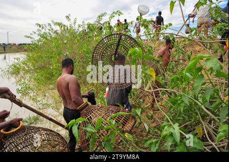 Non esclusiva: 28 novembre 2023 Sylhet-Bangladesh: Le persone rurali armate di trappole di pesce di bambù e rete prendono parte a festeggiare in un inverno di 200 anni f Foto Stock