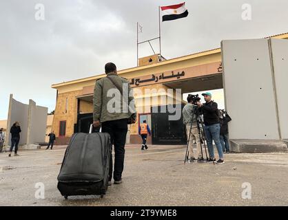 Rafah, Egitto. 27 novembre 2023. Mohammed Abu Raida tira la sua valigia al valico di frontiera di Rafah sulla via del ritorno alla sua famiglia nella Striscia di Gaza. Pochi luoghi sono simbolicamente carichi nella guerra di Gaza come il valico di frontiera egiziano di Rafah. (Al dpa "raggiungere il confine: Una visita al valico di Rafah") credito: Johannes Sadek/dpa/Alamy Live News Foto Stock