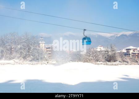 Bansko, Bulgaria, inverno presso la stazione sciistica bulgara con piste da sci, cabine di cabine per impianti di risalita, case innevate e montagne sullo sfondo Foto Stock