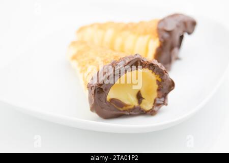 delizioso cannolo siciliano cannellino dolce con pasticceria cioccolato alle nocciole e crema pasticcera, pasta sfoglia italiana su fondo bianco, concetto nutrizionale e dietetico Foto Stock