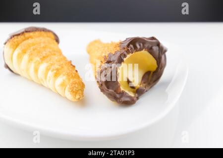 delizioso cannolo siciliano cannellino dolce con pasticceria cioccolato alle nocciole e crema pasticcera, pasta sfoglia italiana su fondo bianco, concetto nutrizionale e dietetico Foto Stock