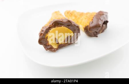 delizioso cannolo siciliano cannellino dolce con pasticceria cioccolato alle nocciole e crema pasticcera, pasta sfoglia italiana su fondo bianco, concetto nutrizionale e dietetico Foto Stock