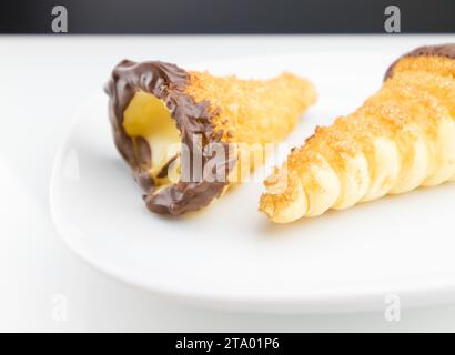 delizioso cannolo siciliano cannellino dolce con pasticceria cioccolato alle nocciole e crema pasticcera, pasta sfoglia italiana su fondo bianco, concetto nutrizionale e dietetico Foto Stock