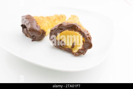 delizioso cannolo siciliano cannellino dolce con pasticceria cioccolato alle nocciole e crema pasticcera, pasta sfoglia italiana su fondo bianco, concetto nutrizionale e dietetico Foto Stock