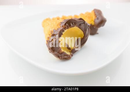 delizioso cannolo siciliano cannellino dolce con pasticceria cioccolato alle nocciole e crema pasticcera, pasta sfoglia italiana su fondo bianco, concetto nutrizionale e dietetico Foto Stock