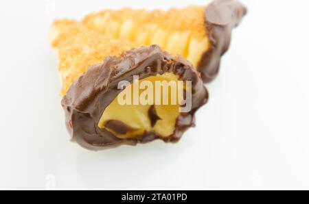 delizioso cannolo siciliano cannellino dolce con pasticceria cioccolato alle nocciole e crema pasticcera, pasta sfoglia italiana su fondo bianco, concetto nutrizionale e dietetico Foto Stock