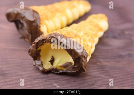 delizioso cannolo siciliano cannellino dolce con pasticceria cioccolato alle nocciole e crema pasticcera, pasta sfoglia italiana su fondo di legno, concetto nutrizionale e dietetico Foto Stock