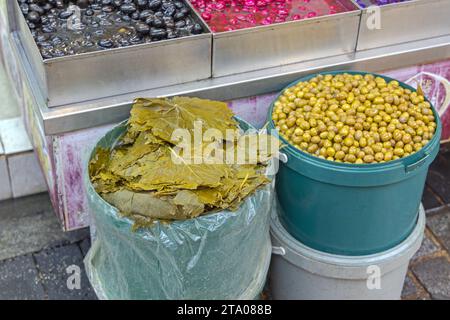 Foglie di vite e Olive marinate in secchi al mercato agricolo Foto Stock