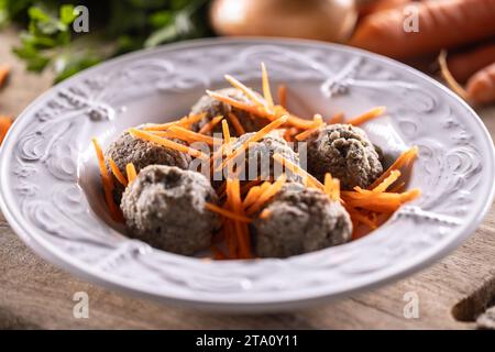 Gnocchi di fegato a base di fegato di manzo, pane, uova e prezzemolo cotti in brodo di manzo messi in un piatto con carote grattugiate. Foto Stock