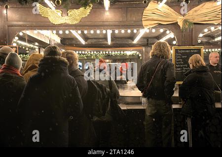 La gente si mette in fila per comprare cibo al mercatino di Natale del castello di Charlottenburg, mentre nevica Berlino, in Germania Foto Stock