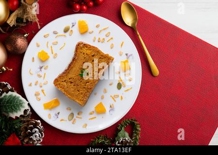 Deliziosa torta vegana di carote e mandarino con mandorle macinate. Cibo natalizio servito su un tavolo decorato con motivi natalizi. Foto Stock