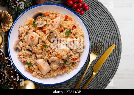 Paella di riso con tacchino e verdure. Ricetta sana. Cibo natalizio servito su un tavolo decorato con motivi natalizi. Foto Stock