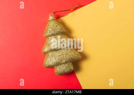Albero di Natale in tinsel dorato su sfondo rosso e giallo. Foto Stock