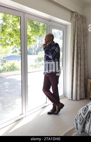 Anziano afroamericano che guarda fuori dalla finestra di casa con spazio per le copie Foto Stock