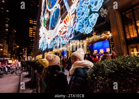 Migliaia di visitatori affollano Saks Fifth Avenue a New York per vedere la loro vetrina natalizia famosa in tutto il mondo e la collaborazione di Saks con Dior per il loro spettacolo di luci, mercoledì 22 novembre 2023 (© Richard B. Levine) Foto Stock