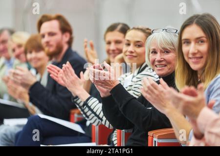 Ritratto di professionisti sorridenti che applaudono mentre si siedono seduti in platea a un evento aziendale nell'auditorium Foto Stock