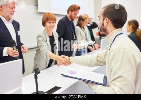 Oratrice femminile che si stringe con un uomo al panel durante un evento aziendale nell'auditorium Foto Stock