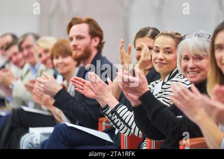 Ritratto di professionisti sorridenti che applaudono mentre si siedono seduti in pubblico alla conferenza aziendale nell'auditorium Foto Stock