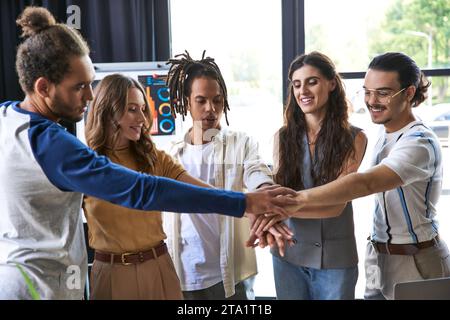allegro team multietnico che si unisce alle mani come segno di unità e collaborazione, moderna cultura delle startup Foto Stock