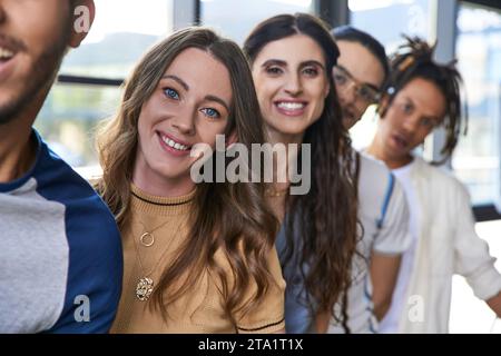 ritratto di un allegro capo di squadra femminile che guarda la fotocamera vicino a colleghi multietnici in un ufficio moderno Foto Stock