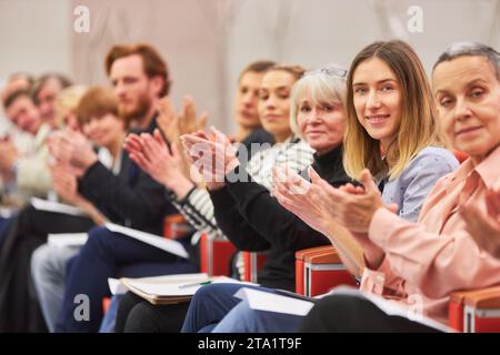Ritratto del sorridente pubblico che applaude mentre si siede seduti ad un evento aziendale nell'auditorium Foto Stock