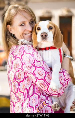 Una femmina che abbraccia un simpatico cane beagle che si gode i momenti felici mentre entrambi guardano la fotocamera Foto Stock
