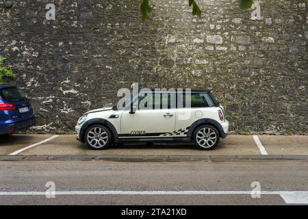 Mini Cooper bianca parcheggiata accanto a un vecchio muro di pietra a Zara, Croazia. 21 settembre 2023. Foto Stock