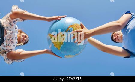 Una ragazza e un ragazzo girano un globo del mondo. Il concetto di pace e creazione. Foto Stock