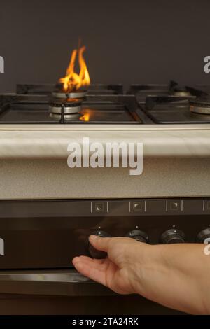 La mano della donna che accende il gas sul concetto di costo energetico della stufa da cucina Foto Stock