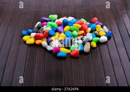 Pila di piccoli ciottoli colorati su sfondo di legno Foto Stock