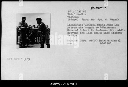 Il tenente generale Hoang Xuam Lam passa il martello al tenente generale Robert E. Cushman Jr., mentre guidano l'ultimo picco nel Liberty Bridge durante una cerimonia il 18 settembre 1967. Questa fotografia cattura il momento di questo significativo evento militare durante la guerra del Vietnam. Foto Stock