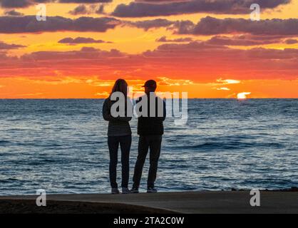 Una giovane coppia guarda il tramonto sul Mar Mediterraneo, Paphos, Cipro Foto Stock